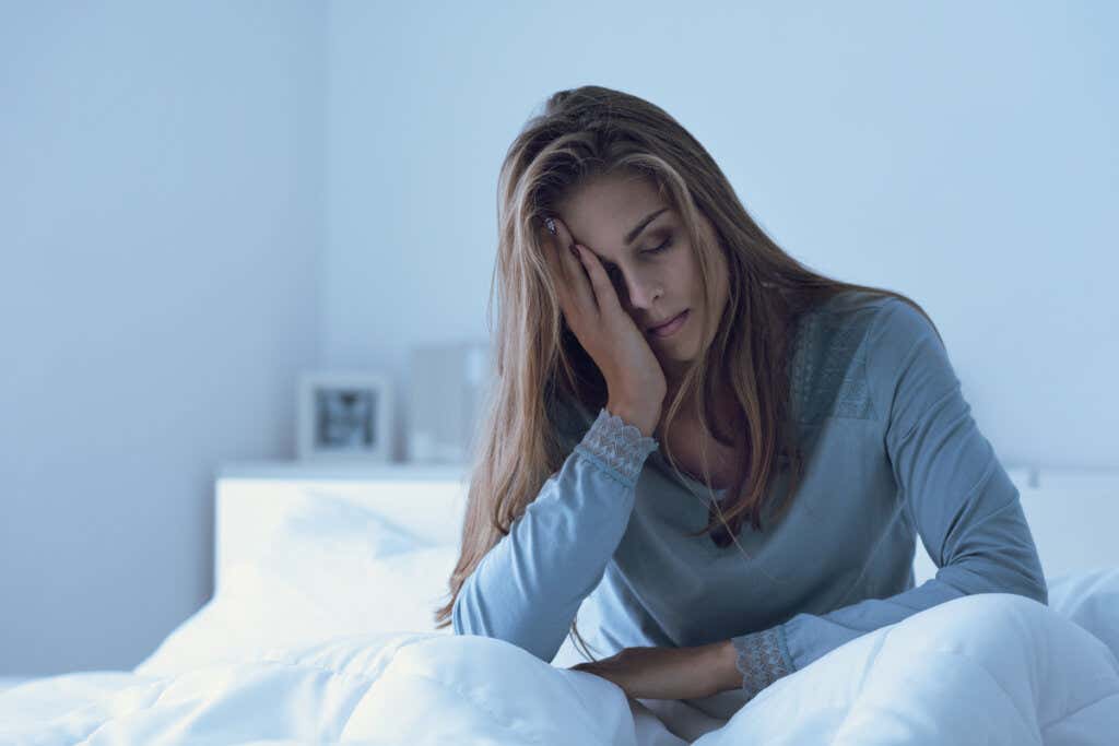 Mulher triste na cama pensando nas emoções que enfraquecem seu sistema imunológico