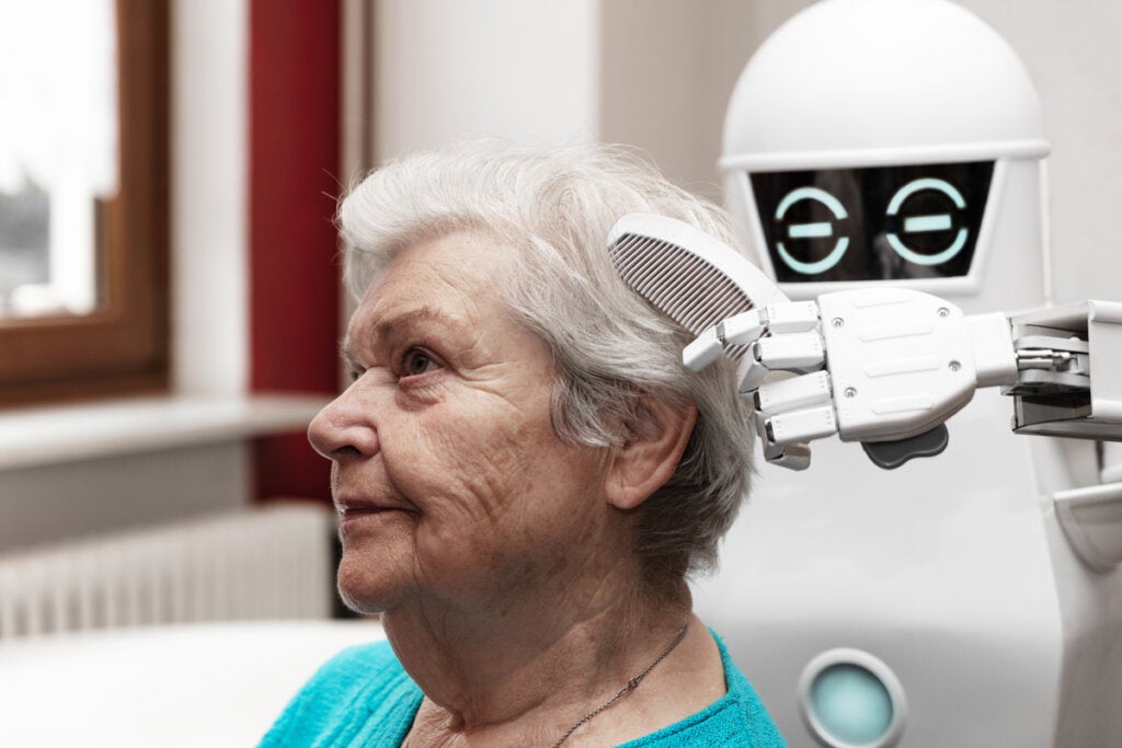 Robot che pettina una donna anziana.