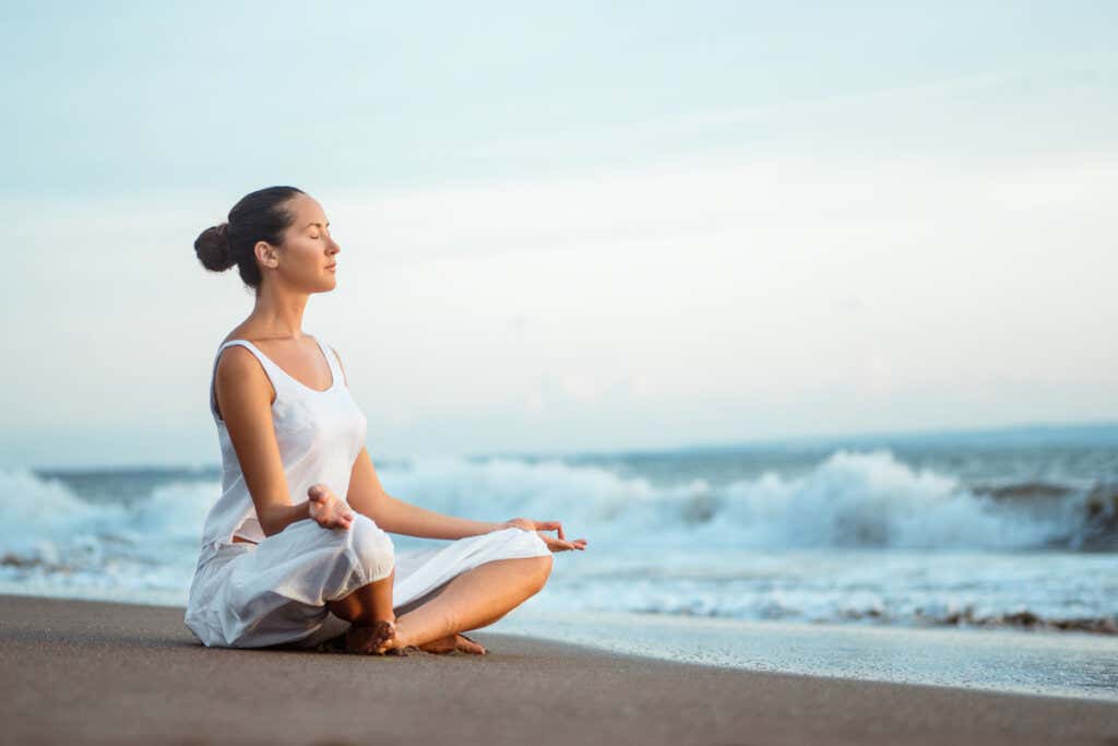 Donna che medita sulla spiaggia per curare l'assenza del ciclo mestruale.