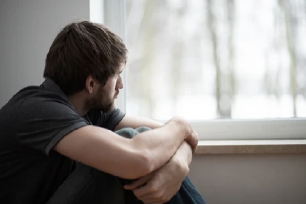 Hombre mirando desde una ventana con ganas de huir