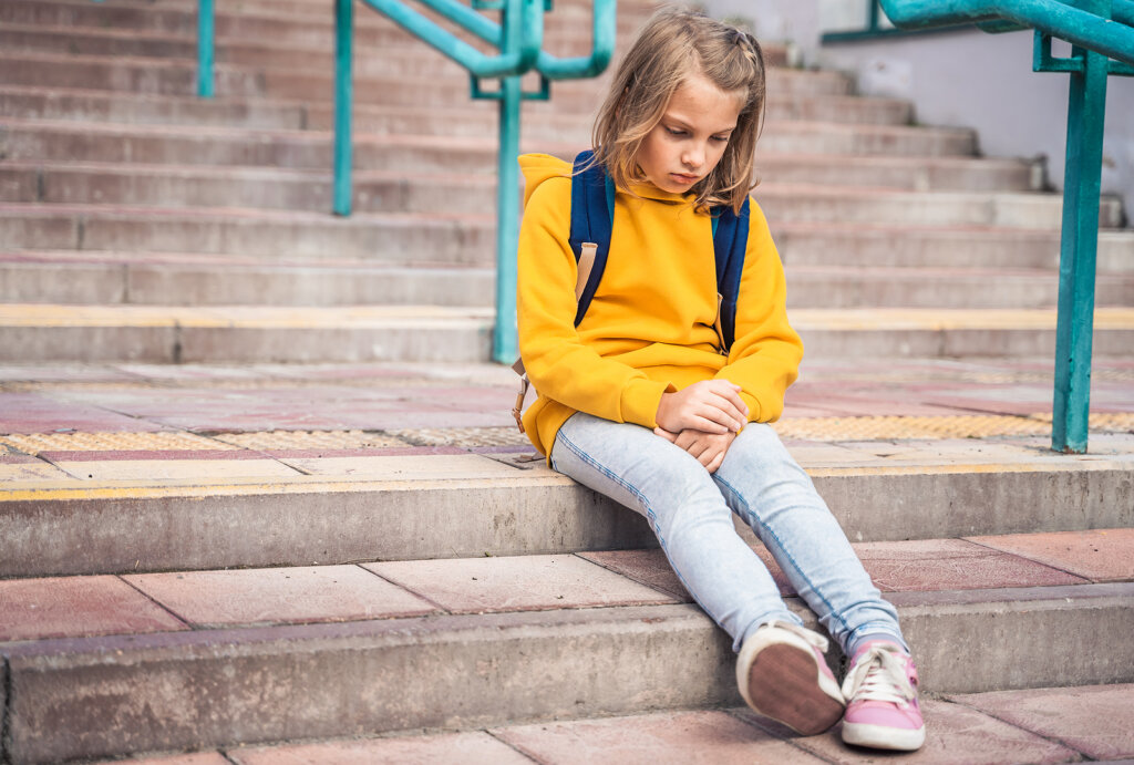 Niña sola en las escaleras del colegio