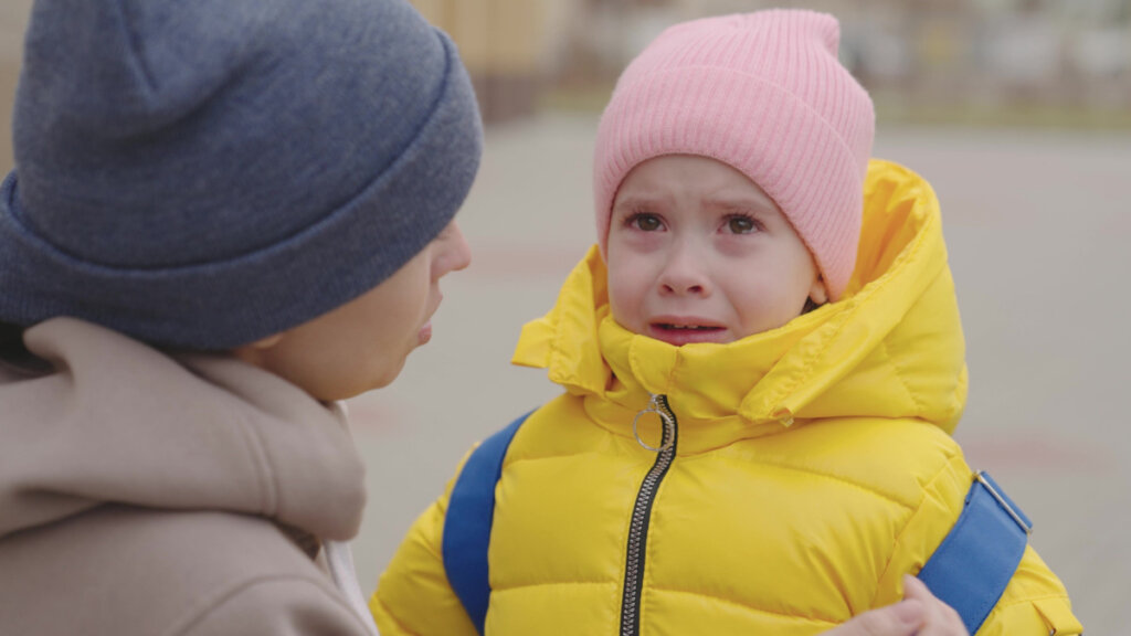 Niño llorando con su madre en la puerta del colegio