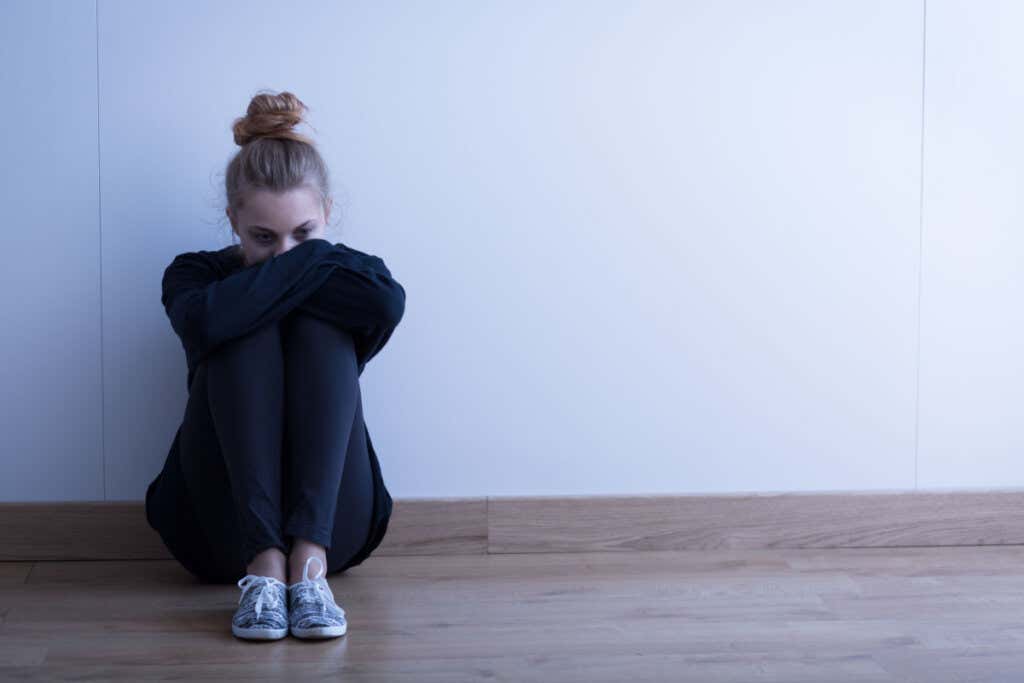 Chica con anorexia sentada en el suelo