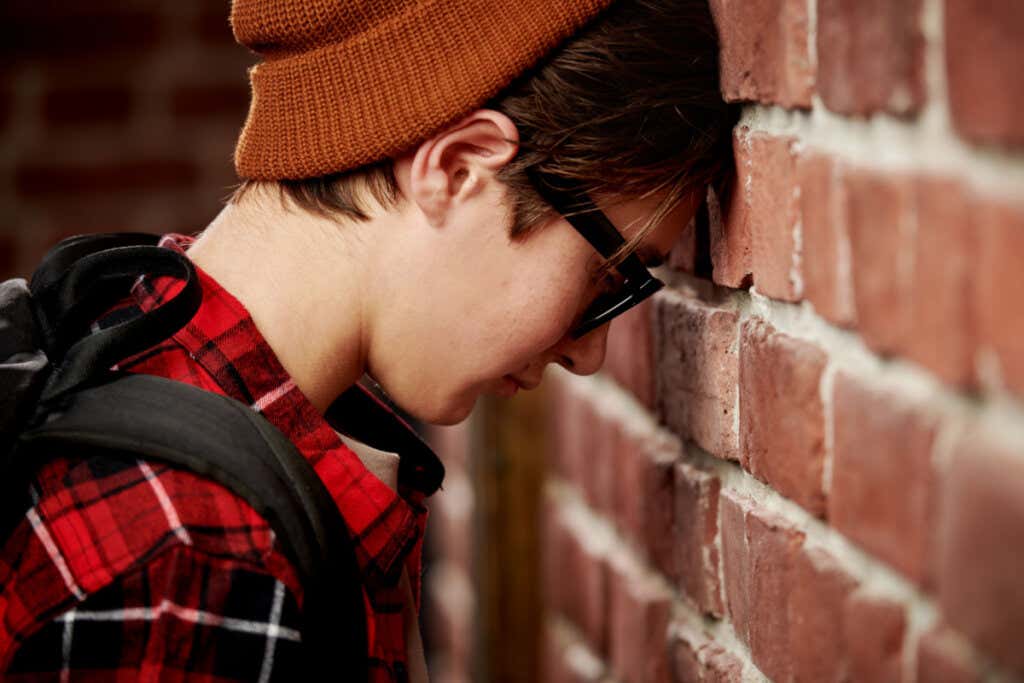 Surullinen poika nojaa päätään seinään.