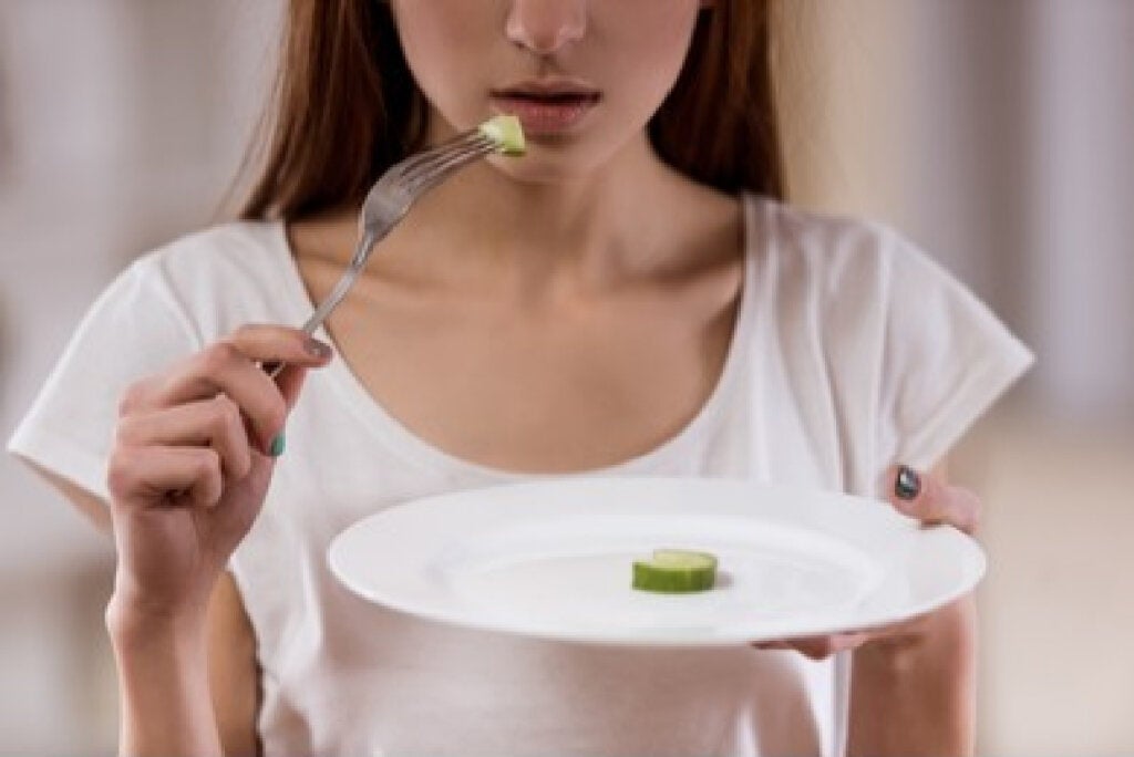 Mujer comiendo con poca comida en el plato