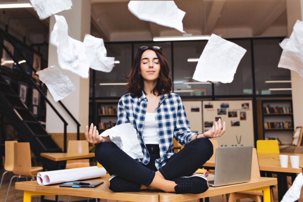 Arbeitsbedingter Stress: Frau meditiert auf ihrem Schreibtisch