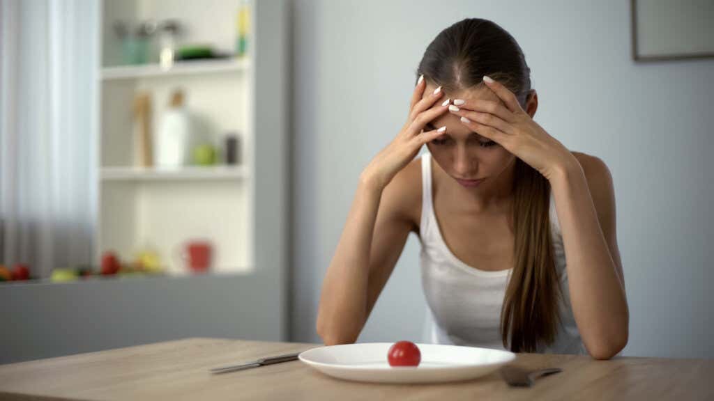 Trist kvinne som ser på tallerkenen og viser kjennetegn ved et uløst traume