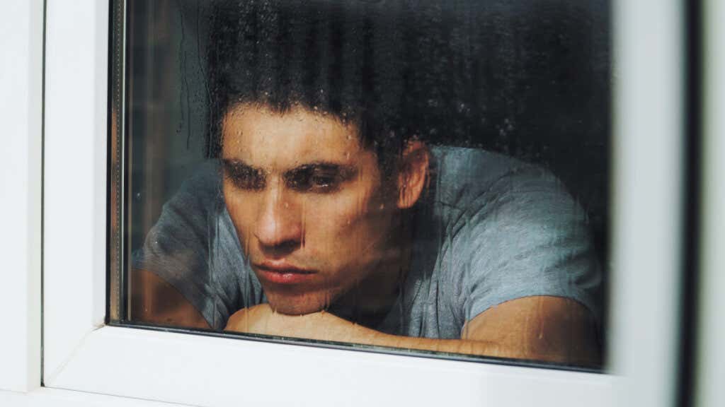 Ledsen pojke tittar ut genom fönstret