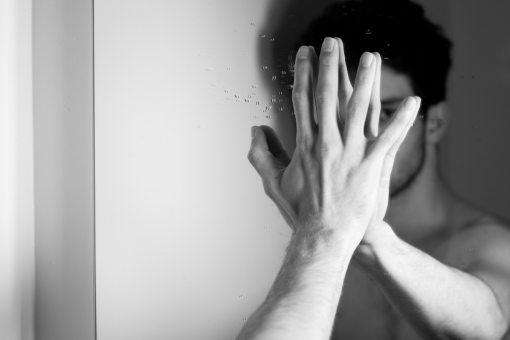 Homme couvrant son reflet dans un miroir