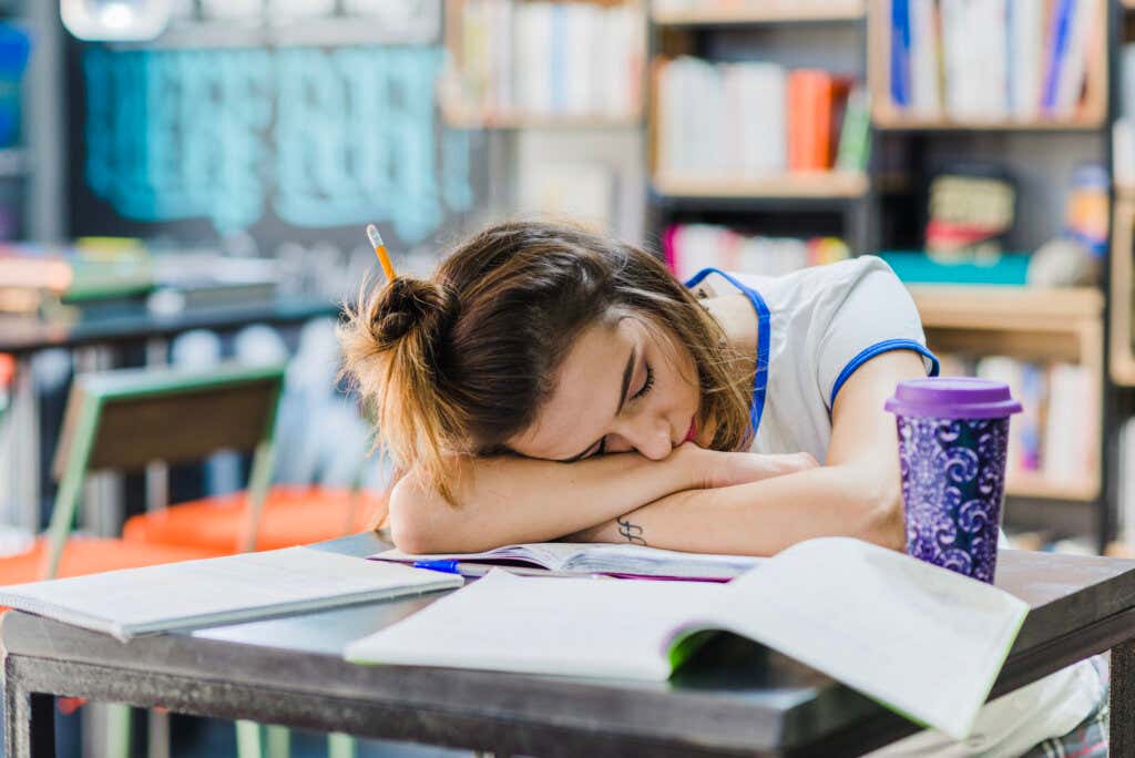 junge Frau hat das Schlafphasensyndrom und schläft am Schreibtisch