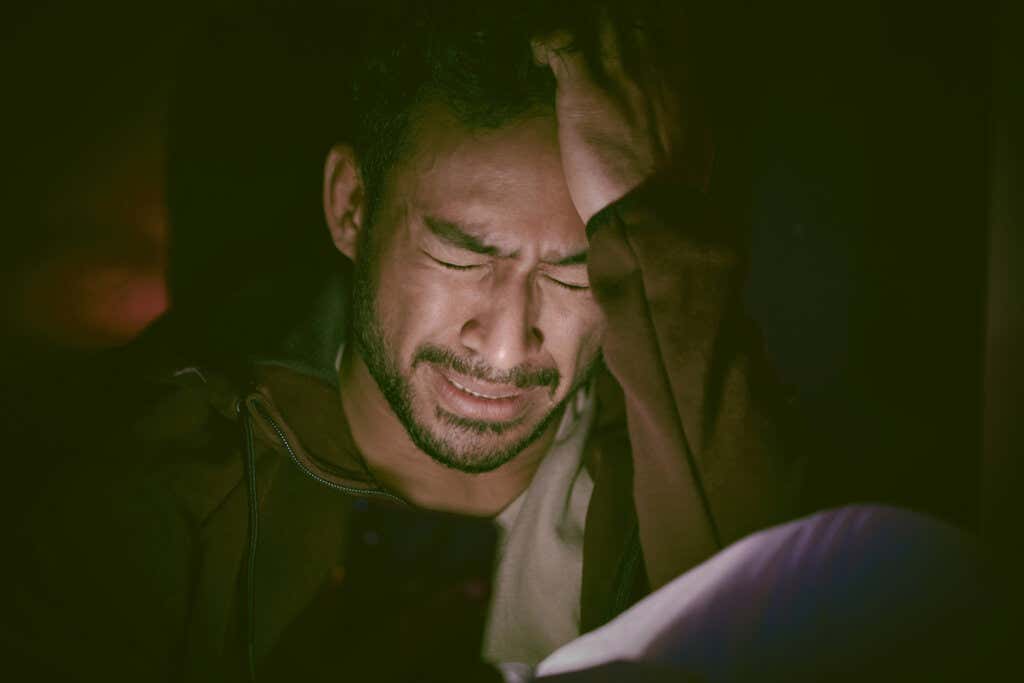 Mann som gråter i mørket på grunn av emosjonelt sjokk