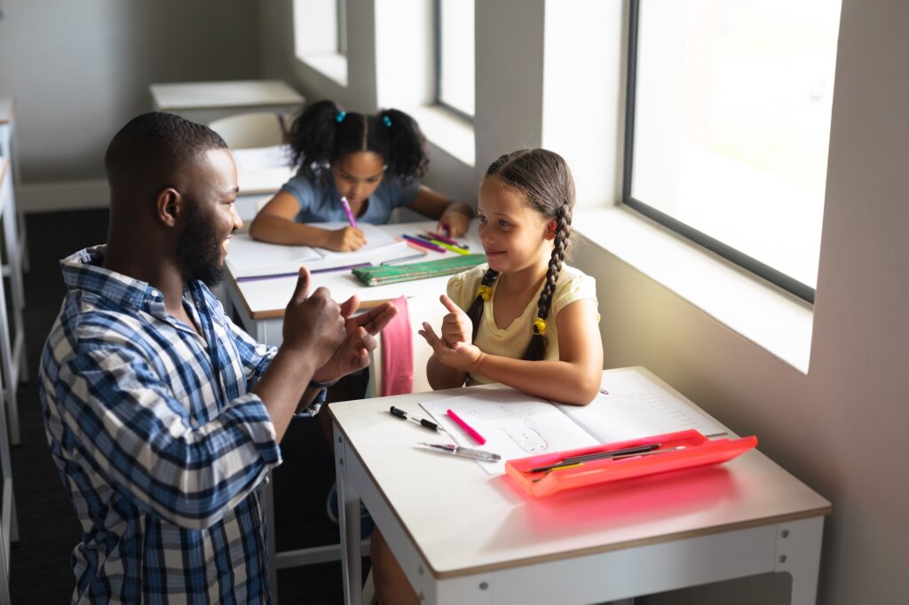 Nauczyciel uczy języka migowego studenta w klasie