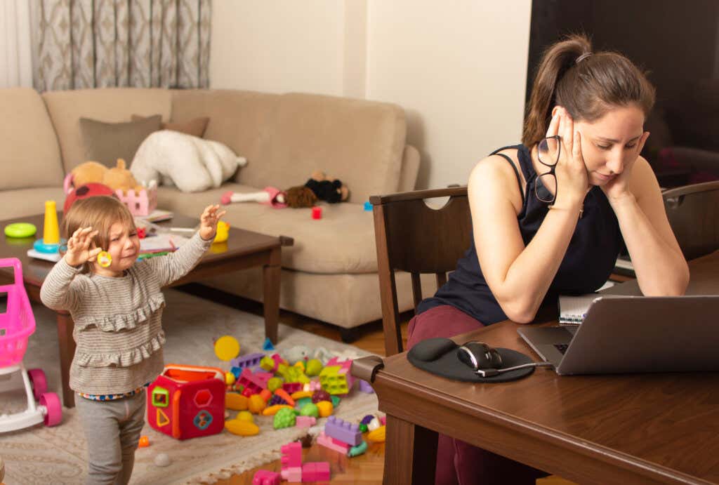 Une fille pleure dans une pièce avec des jouets par terre et attend que sa mère fatiguée vienne la chercher