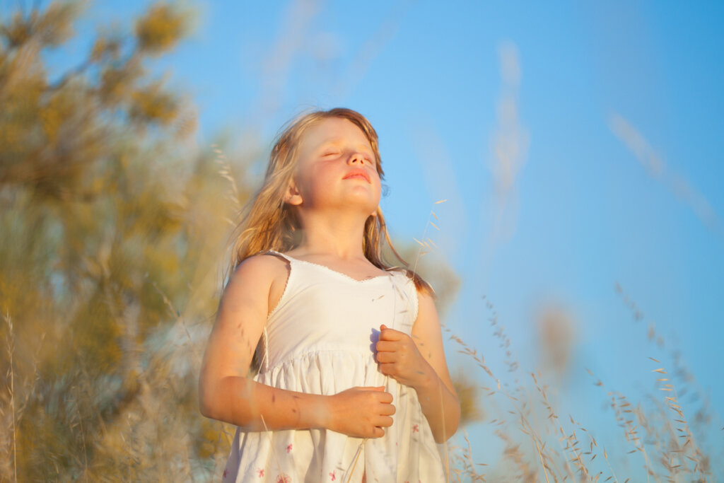 Chica en el campo respira aire puro durante ejercicio de mindfulness para niños