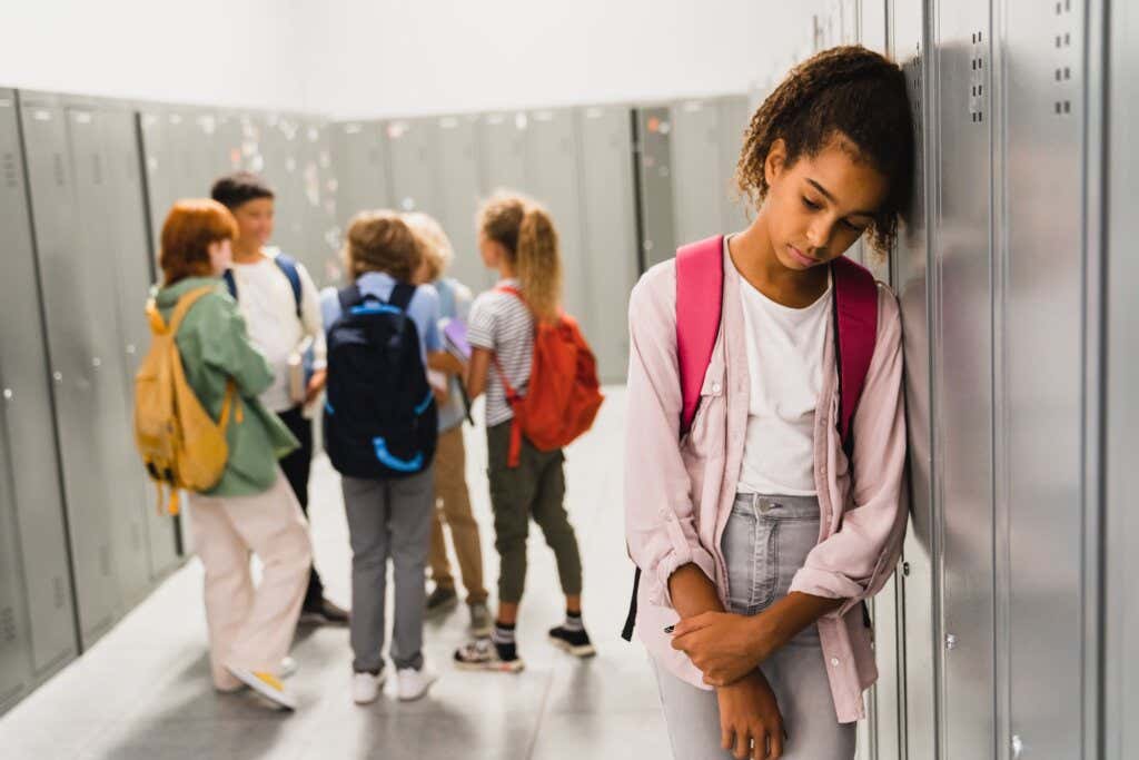 I bambini ignorano la ragazza che siede da sola nel corridoio della scuola