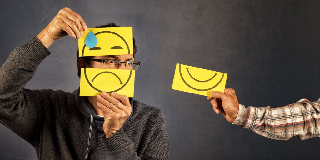 Person holding sign of happy face and sad face