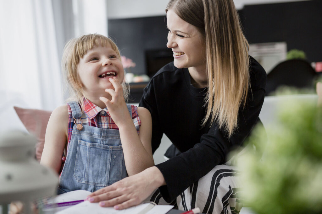 Mère et fille rient en faisant leurs devoirs