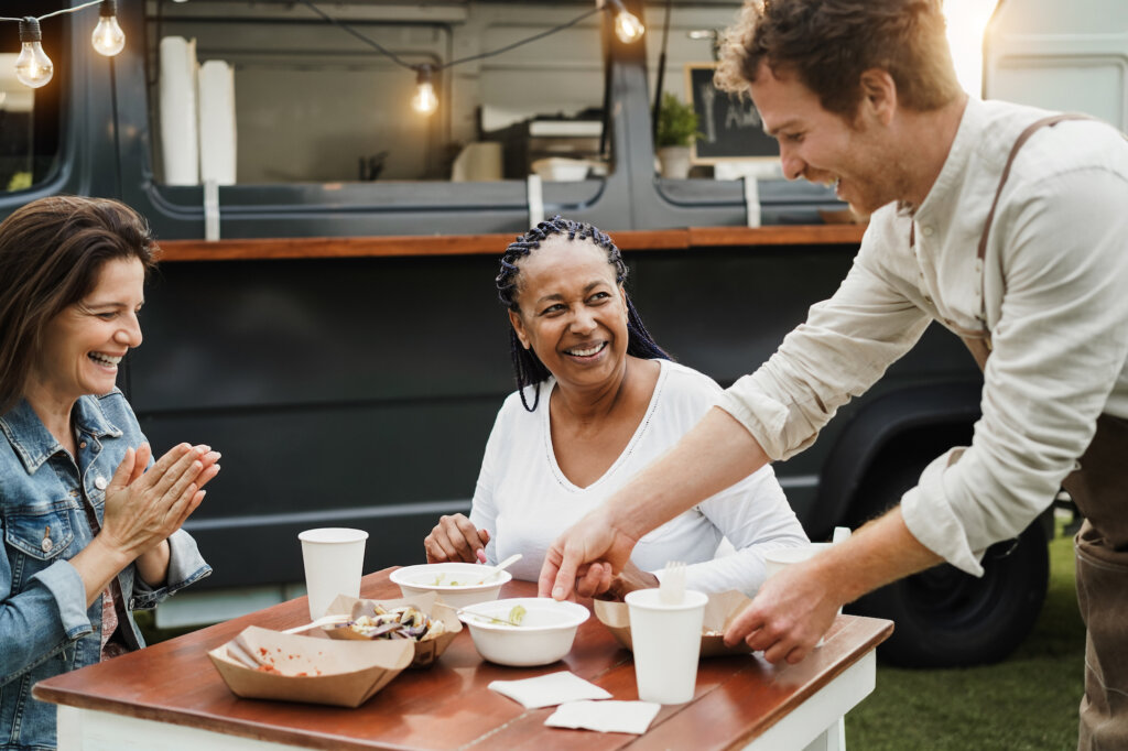 Le serveur enlève les assiettes de la table où les clientes sourient