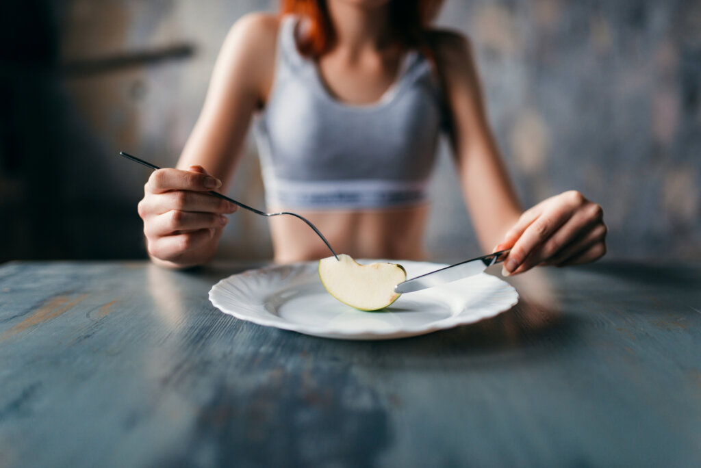 Young victim of eating disorder eats a piece of apple