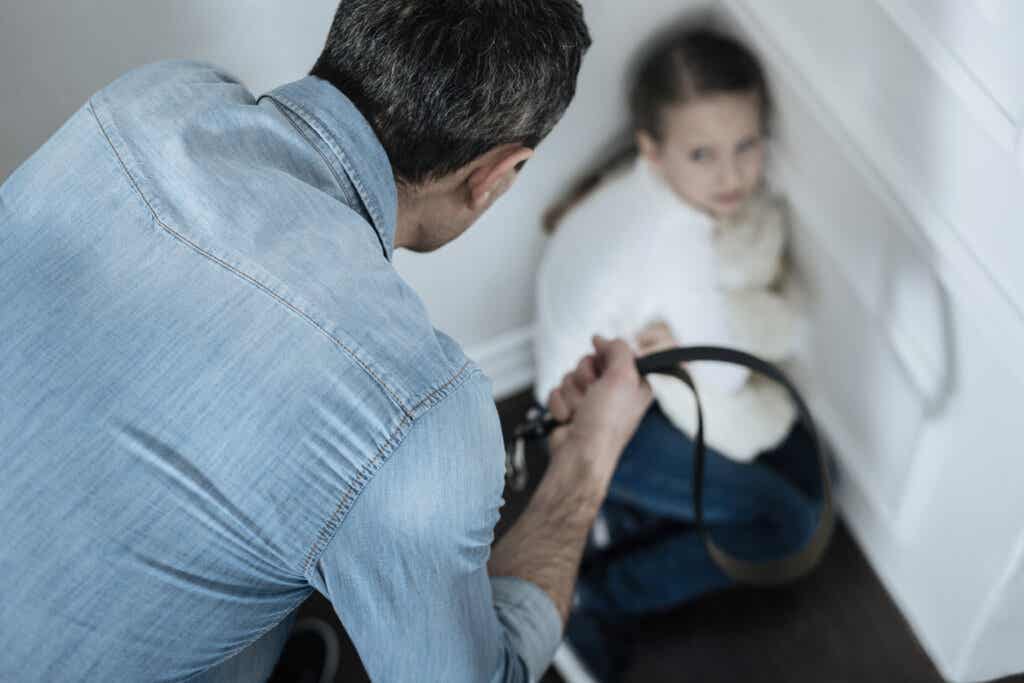 Father with a belt in hand mistreats a girl