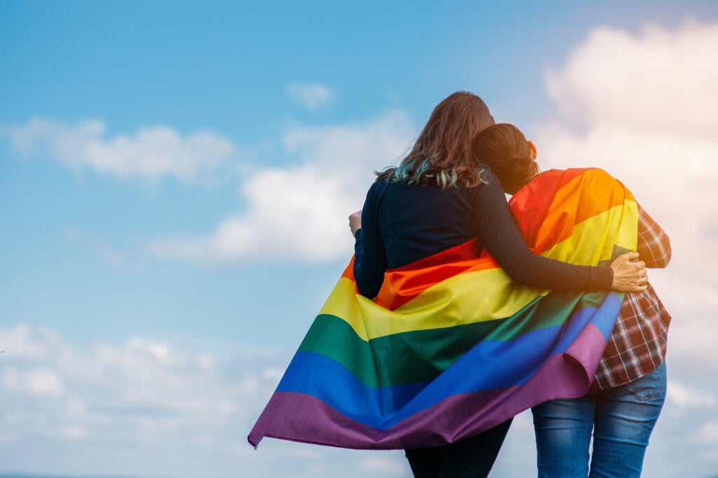 Embracing lesbian couple with the flag of the LGTB community