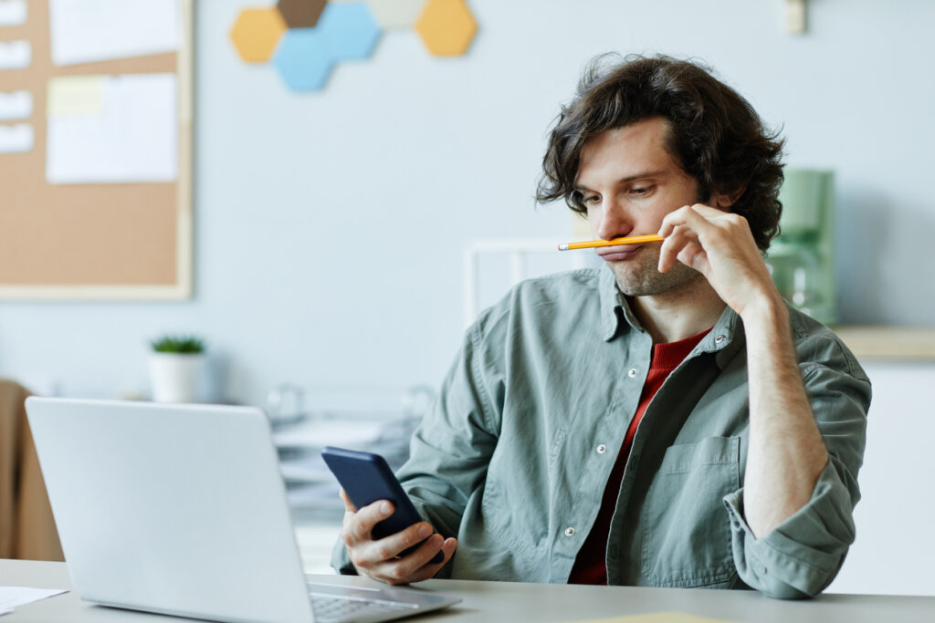 Man puts a pencil in his mouth, distracted from his work as a consequence of ADHD in adults