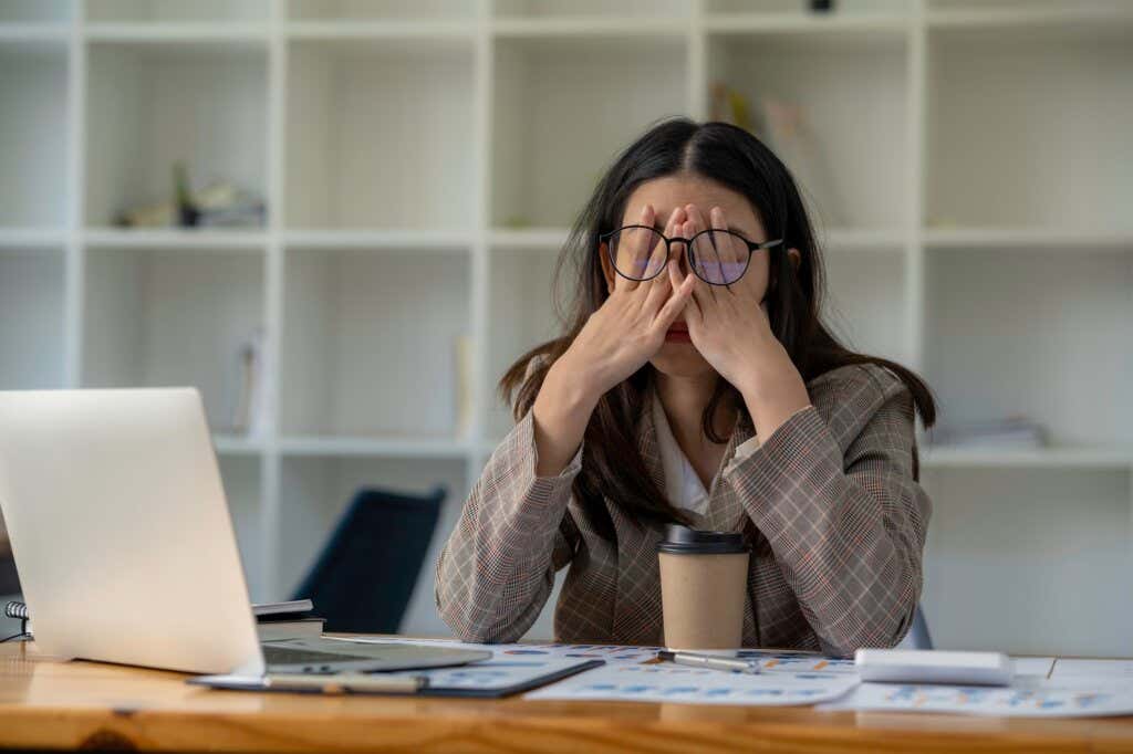 Kvinne frustrert over arbeidsproblemer dekker ansiktet med hendene
