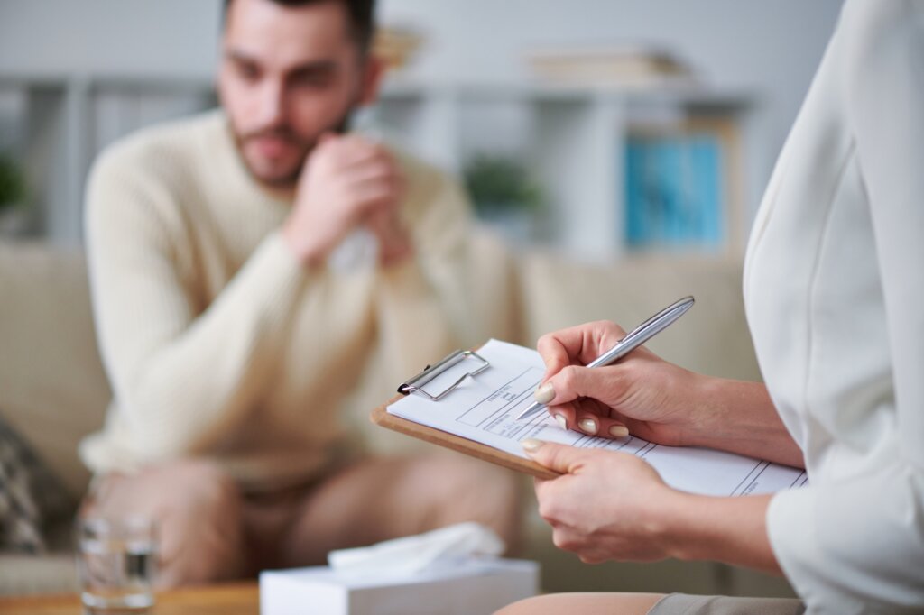 L'homme soulève ses problèmes dans une sexothérapie avec un spécialiste qui prend des notes