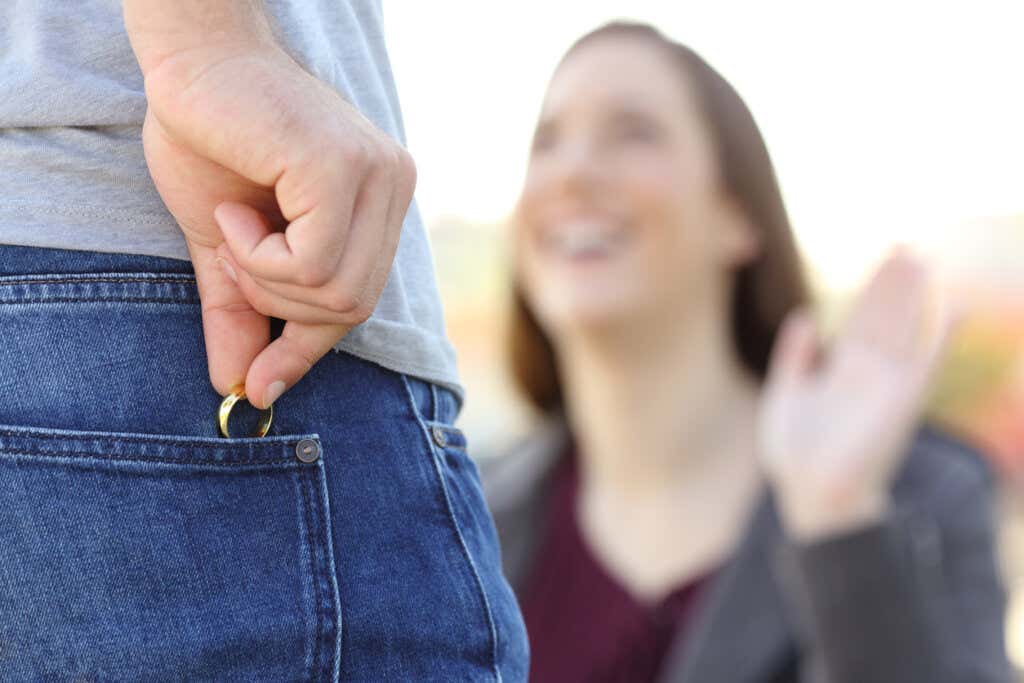 Mannen gjemmer gifteringen sin i lommen for å flørte med en kvinne