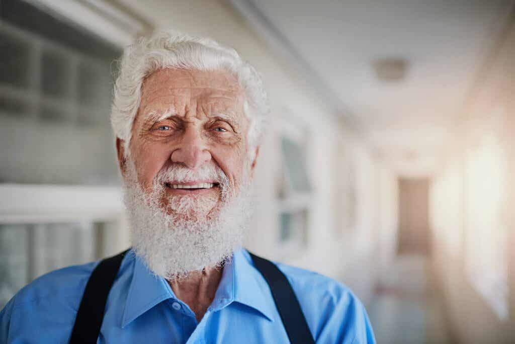 Adulto mayor sonríe en un largo pasillo y demuestra lo positivo de cómo cambia la personalidad mientras envejece