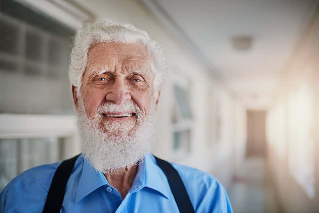 Un adulte plus âgé sourit dans un long couloir et démontre le positif de la façon dont la personnalité change avec l'âge