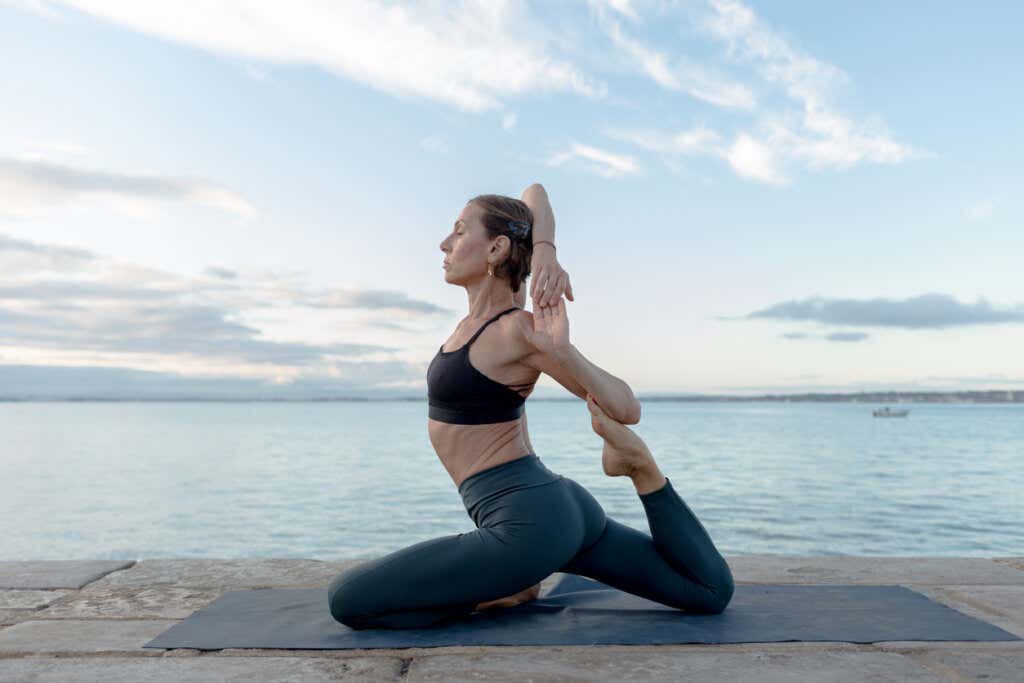 Vrouw doet yoga aan zee