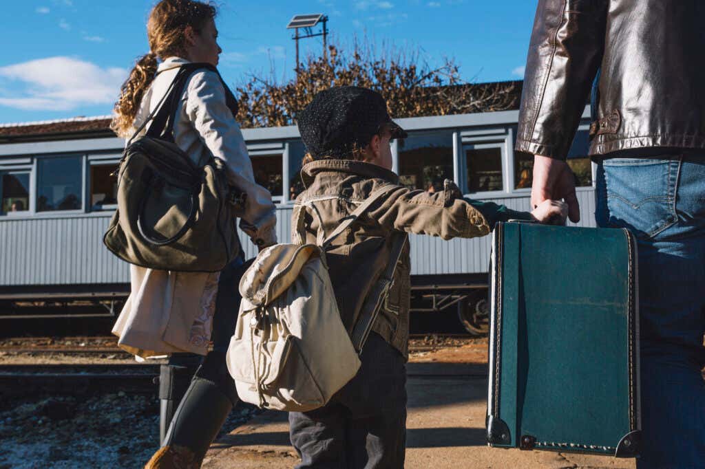 Rodzina uchodźców wojennych idzie z torbami i walizkami