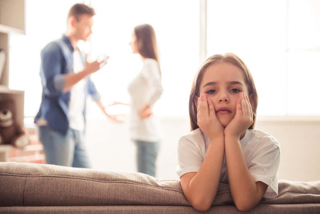 Triest kind met op de achtergrond ruziënde ouders