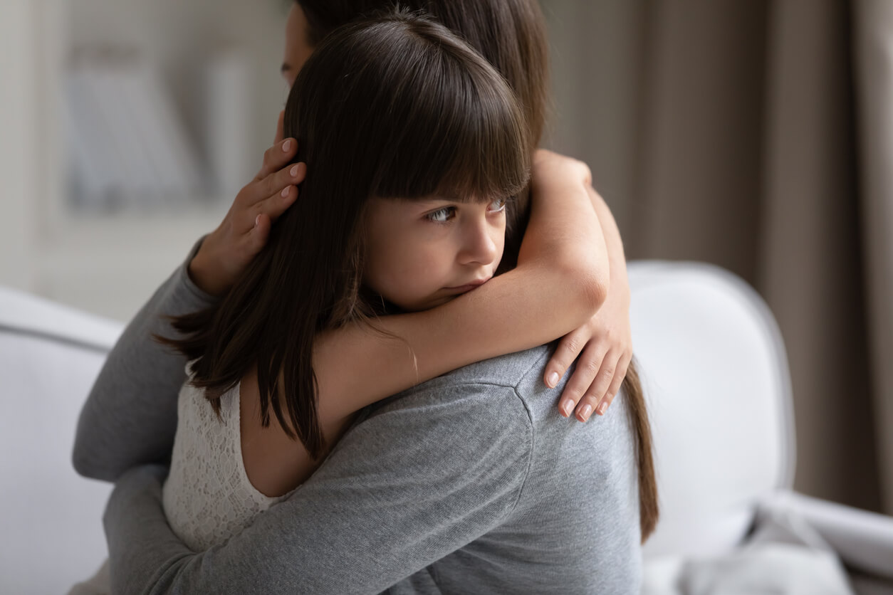 Niña recibe abrazo de su madre. Apego seguro.