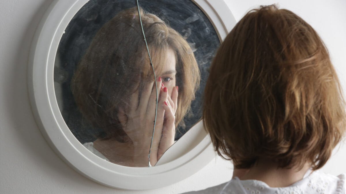 Femme devant un miroir brisé.