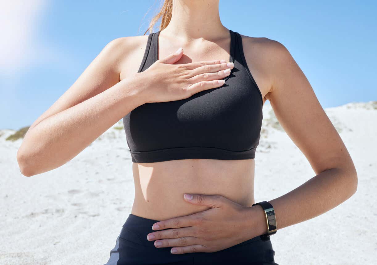 Mujer practica respiración diafragmática con una mano en el pecho y otra en el diafragma. 