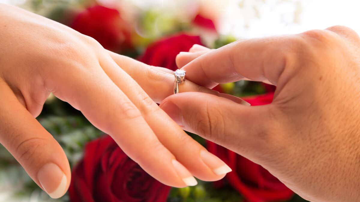 Hombre pone anillo de compromiso en el dedo de su pareja.
