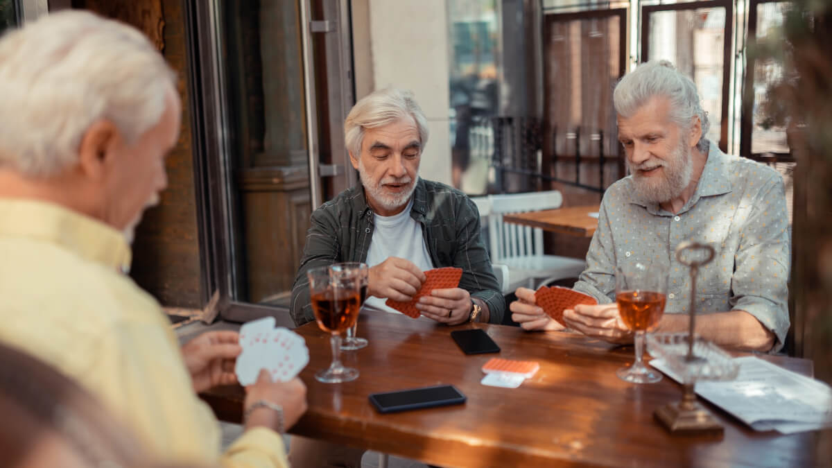 Tres hombres mayores jugando cartas. 